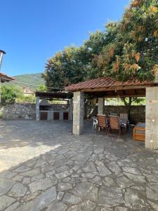 a stone patio with a pavilion with chairs and a table at Christina's Apartment in Stratónion