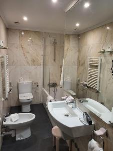 a bathroom with a sink and a tub and a toilet at Hotel Leonor Mir&oacute;n in Soria