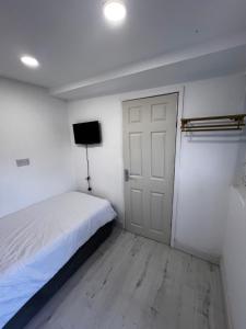 a bedroom with a bed and a door and a television at Ensuite Box Room in Corby NN17 in Rockingham