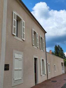 a building with white shuttered windows on it at Maison Commandant Blaison in Lapalisse
