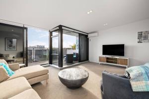 a living room with a couch and a tv at The Lookout - Mount Maunganui in Mount Maunganui