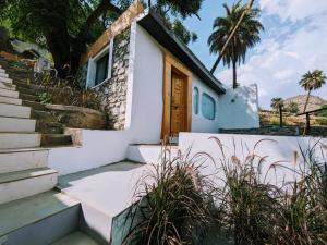 a white house with stairs and a door at Cob House in Mount Ābu