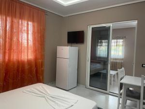 Habitación con nevera blanca, mesa y silla. en Vila Topi, en Vlorë