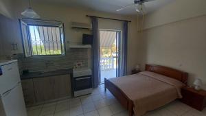 a bedroom with a bed and a kitchen with a refrigerator at Avouris Studios in Kypseli