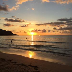 a sunset on the beach with people in the water at Eden Island P238A13 Lux Apartment in Mahe