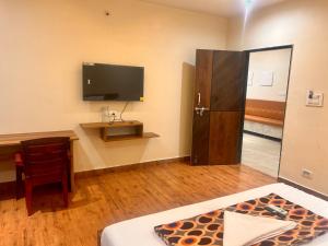 a room with a bed and a desk and a television at SV Banquets And Luxury Rooms in Farrukhnagar