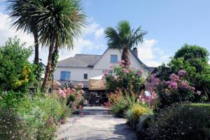 a white house with palm trees and flowers at Maison CHILO in Barcus