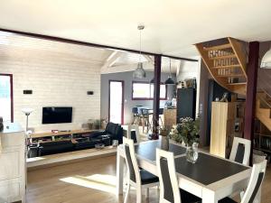 a dining room and living room with a table and chairs at Villa Lou Bercail HOURTIN - 10 personnes in Hourtin