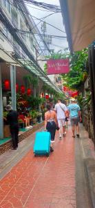 un groupe de personnes marchant sur un trottoir avec une valise bleue dans l'établissement Bann Chana BKK, à Bangkok