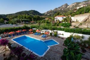 a swimming pool with chairs and umbrellas in front of a mountain at Apartments Dimitra in Kámpos