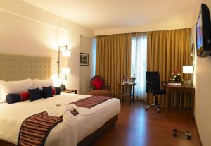 a hotel room with a large bed and a desk at Royal Orchid Central Jaipur, Bani Park in Jaipur