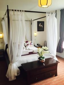 a bedroom with a bed with white curtains and a table at Park Central Hotel in Bournemouth