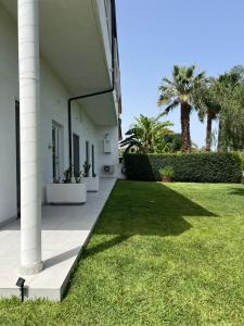 a porch of a house with grass and palm trees at Appartamento Da Maria in Caulonia Marina