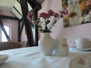 Biały wazon z kwiatami siedzący na stole w obiekcie Hotel Carl von Clausewitz w mieście Burg