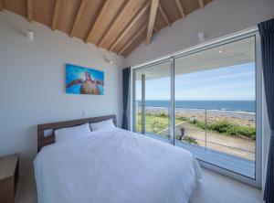 a bedroom with a bed and a view of the ocean at CHLOROBIANCO amami in Amami