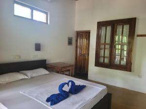a bedroom with a bed with a blue ribbon on it at Galaxy Lounge in Arugam Bay