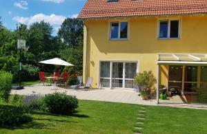 ein gelbes Haus mit einer Terrasse, einem Tisch und Stühlen in der Unterkunft Oase im Dresdner Westen in Dresden