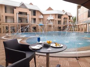 a table and chairs in front of a swimming pool at Royal Orchid Central Kireeti-HAMPI Hospet in Hampi