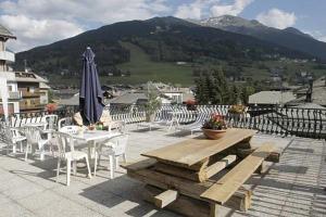 patio con tavolo, sedie e ombrellone di Hotel Gufo a Bormio