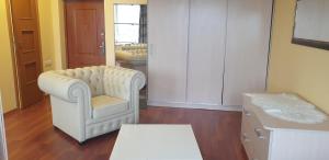 a living room with a white chair and a table at Small family apartment in Klaipėda +1 photo