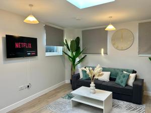 a living room with a couch and a clock on the wall at Folkestone Harbour 1 Bed Apartment F4 in Kent