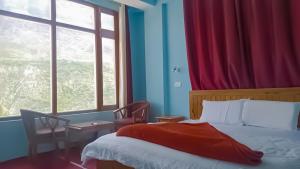 a bedroom with a bed and a large window at Hotel Ranika Inn Keylong in Kyelang