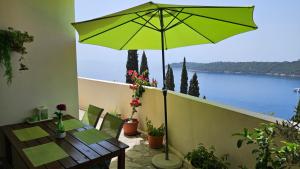 a green umbrella on a balcony with a view of the water at Apartment Matea Zlatni Potok in Dubrovnik