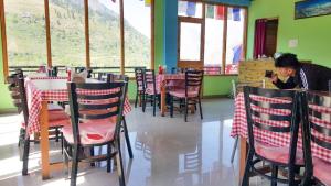 a woman sitting at a table in a restaurant at Pine Corn Guest House in Kyelang