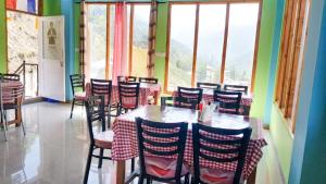 a dining room with tables and chairs and windows at Pine Corn Guest House in Kyelang +1 photo
