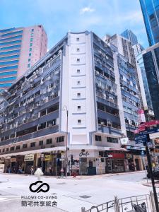 a large white building in a city with tall buildings at Pillows CoLiving in Hong Kong