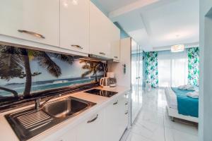 a kitchen with white cabinets and a sink and a bed at Dream Boutique Apartments in Nikiti