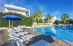 eine Gruppe von Stühlen und einem Sonnenschirm neben einem Pool in der Unterkunft Gorgeous Home In Marina Di Ragusa in Marina di Ragusa + 15 Fotos