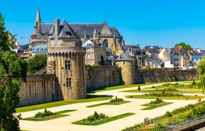 a castle with a garden in front of a city at Charmant studio avec terrasse hyper-centre de Vannes à 5 min du Port et des Remparts in Vannes