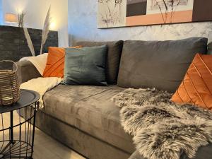 sala de estar con sofá gris y almohadas de color naranja en Ferienwohnung Augenblicke, en Olsberg