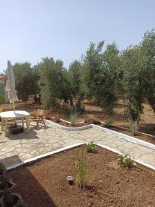 a patio with a table and a bench and trees at Kalelia in Nea Potidaea