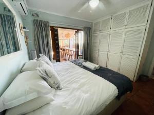 a bedroom with a large bed with white sheets and pillows at 4 Bedroom Beach House on 4th Ave in Umdloti