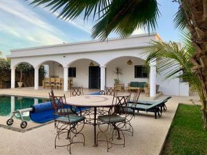 a patio with a table and chairs next to a pool at Villa Aloha in Somone