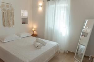 a white bedroom with a bed with two pillows on it at Aloni in Áno Meriá