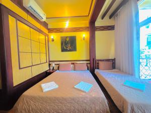two beds in a room with yellow walls at Bi Saigon Hotel in Ho Chi Minh City