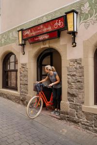 Eine Frau steht mit einem Fahrrad vor einem Gebäude. in der Unterkunft AKZENT Hotel Berg's Alte Bauernschänke- Wellness und Wein in Rüdesheim am Rhein