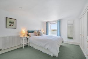 a white bedroom with a bed and a window at N ° 42 The Salcombe in Salcombe