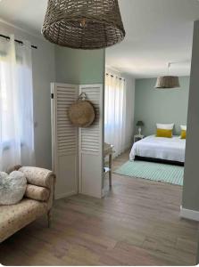a bedroom with a bed and a couch and a chair at Jolie Villa en bois au calme in Arès