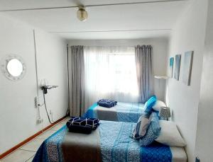 two beds in a bedroom with a window at Bokkomblommetjie in Lambertʼs Bay