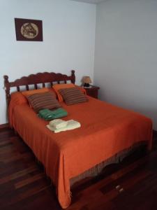 Un dormitorio con una cama con una manta naranja. en Departamento Los Pinos, en Salta