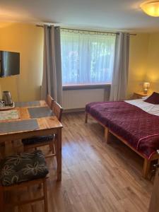 a bedroom with a bed and a table and a window at Willa Zuza in Kołobrzeg +8 photos