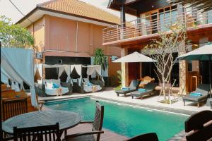 a swimming pool with chairs and a table next to a building at De Olas Padang Padang Bali in Uluwatu