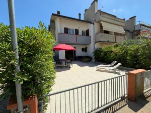 a patio with a red umbrella in front of a house at Villetta a 200 m dalla riva in Lido di Classe