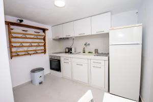 a kitchen with white cabinets and a refrigerator at Ostria kythnos apartment in Kithnos