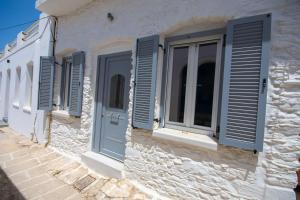 a row of blue shutters on a white building at Ostria kythnos apartment in Kithnos