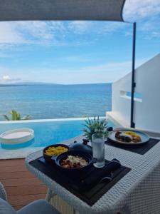 a table with two plates of food on it with the ocean at Epic Suites Bohol ADULTS ONLY in Dauis